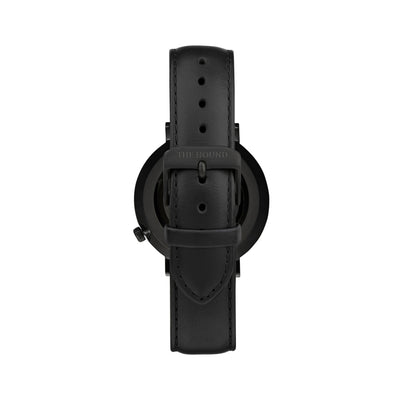 Matte black and black watch with a stitched black genuine leather band and matte black buckle designed by THE HOUND, styled done up and shot from behind.