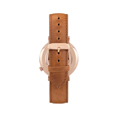 Rose gold and white watch with a stitched tan genuine leather band and rose gold black buckle designed by THE HOUND, styled done up and shot from behind.